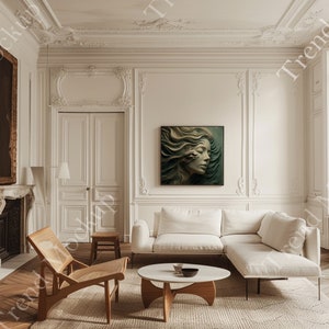May include: A stylish living room featuring a white corner sofa, a circular coffee table, and a wooden chair. A framed artwork of a woman's profile with flowing hair adorns the wall. The room has white walls and decorative mouldings.