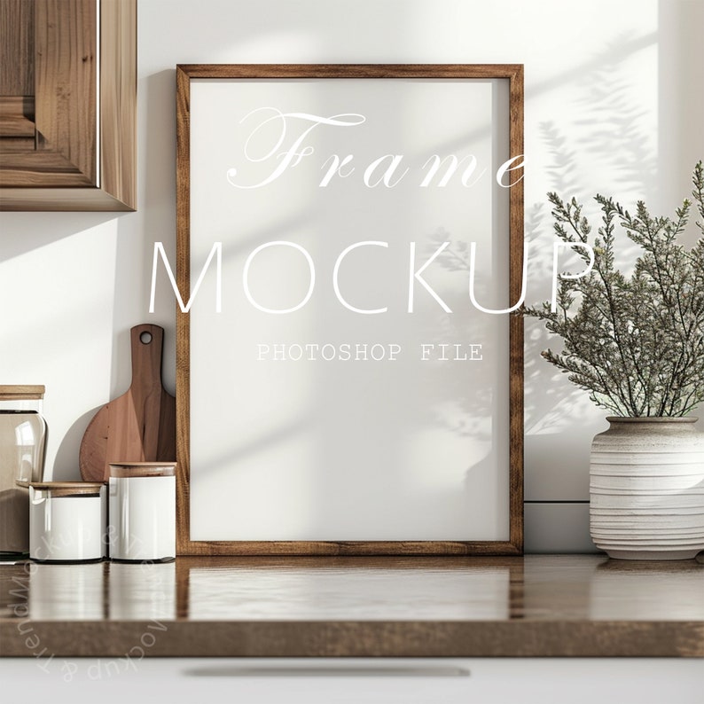 May include: A brown wooden frame mockup with a white background. The frame is sitting on a wooden countertop with a vase of dried flowers and kitchen items in the background. The text "Frame Mockup" and "Photoshop File" is written in white on the frame.