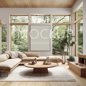 May include: A beige sectional sofa with pillows sits in a living room with large windows overlooking a lush green forest. A round wooden coffee table sits in front of the sofa. A framed mockup is hanging on the wall above the sofa. The text "Frame Mockup Photoshop File" is printed on the wall.