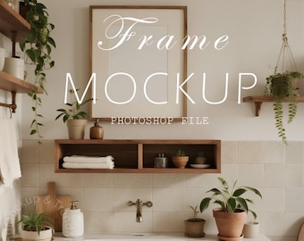 May include: A bathroom scene featuring a large, empty picture frame labeled "Frame Mockup Photoshop File." The room has a neutral color palette with wooden shelves, a sink, and potted plants. The overall aesthetic is minimalist and natural.