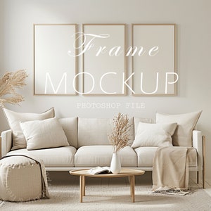 May include: A mockup of three empty picture frames with a gold frame and white matting. The frames are hanging on a white wall above a white sofa with beige pillows and a throw blanket. A vase with dried flowers sits on a wooden coffee table in front of the sofa.