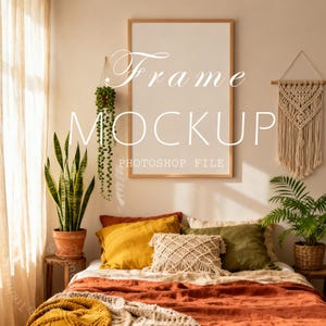 May include: A bedroom scene with a large, empty wooden picture frame labeled "Frame Mockup Photoshop File" above a bed. The bed is covered with orange and beige bedding and pillows in shades of yellow and green. Plants and macrame wall decor add to the cozy aesthetic.