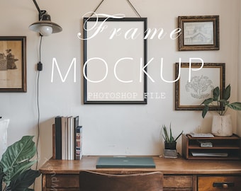 May include: A black frame mockup hanging on a white wall with a wooden desk and chair in front of it. The frame is surrounded by other framed artwork and a plant. The text "Frame Mockup" and "Photoshop File" is written on the wall.