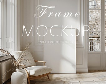 May include: A white frame mockup in a living room setting with a white armchair, a vase with branches, and a rug on a wooden floor. The text "Frame Mockup Photoshop File" is displayed above the frame.