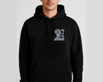 Può includere: Felpa con cappuccio nera con tasca frontale e coulisse. La felpa presenta una grafica grigia di un personaggio con una fascia per la testa e occhiali da sole, con testo giapponese sul lato destro.