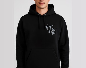 May include: Black hooded sweatshirt with a kangaroo pocket and drawstring. The sweatshirt features a small, gray graphic of stylized figures in motion on the upper left chest. The design includes figures in various poses, suggesting movement or action.