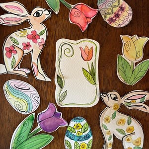 May include: Watercolor Easter-themed cutouts featuring bunnies, tulips, and decorated eggs. The bunnies have floral patterns, and the eggs are adorned with various designs. The tulips are in shades of red, yellow, and purple.
