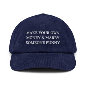 Può includere: Un cappello da baseball in velluto a coste blu navy con testo ricamato bianco che recita "Make your own money & marry someone funny".