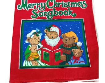 Pode incluir: Um livro de canções de Natal vermelho com o texto "Merry Christmas Songbook" em verde e branco. A capa apresenta um fundo azul com ilustrações de ursinhos de pelúcia vestidos com roupas de Natal, cantando de um livro.