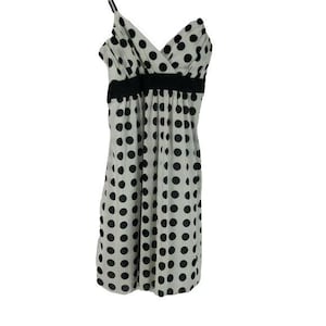 May include: A white sleeveless dress with a black polka dot pattern and a black ribbon around the waist.