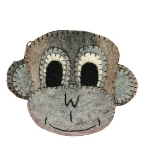 May include: A gray felt monkey-shaped coin purse with black eyes and a stitched smile. The ears and face are a mix of gray and brown felt, with white stitching around the eyes and ears. The zipper is visible at the top.