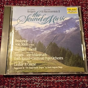 May include: A CD case for "The Sound of Music" with a mountain landscape image. The cover displays the names of the cast and orchestra. The Telarc Digital logo is visible in the top right corner.