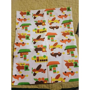 May include: A white fabric with a repeating pattern of colorful toy airplanes and trucks. The toys are in shades of green, orange, brown, yellow, and red.