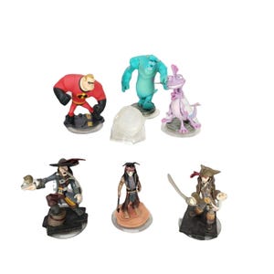 May include: A collection of Disney Infinity character figures. The figures include Mr. Incredible in a red suit, Sulley in blue, a purple lizard, a clear dome, and three pirate figures. The figures are on circular bases.