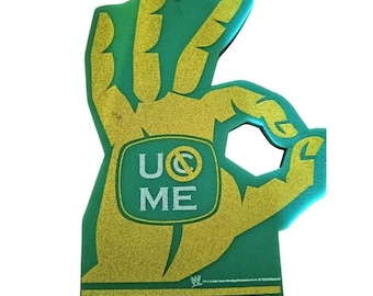Op de afbeelding: Een groene schuimrubberen hand in de vorm van een OK-gebaar met een gouden glitterafwerking. Het midden bevat een groen vierkant met de witte tekst U CAN'T SEE ME. Onderaan toont een horizontale balk de witte tekst CENA APPROVED in hoofdletters.