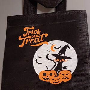 May include: Black reusable tote bag with a white moon and black cat wearing a witch hat. The bag has the text "Trick or Treat" in orange lettering.