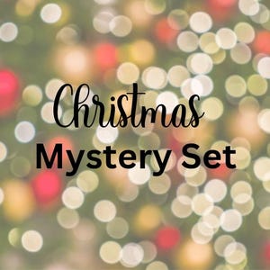 Może przedstawiać: Obraz z rozmytym tłem świateł bożonarodzeniowych w kolorze czerwonym, złotym i białym. Słowa "Christmas Mystery Set" są napisane czarną, elegancką czcionką na tle świateł bokeh.