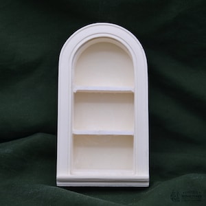 May include: White arched shelf unit with three shelves. The shelf unit is made of plaster and has a smooth finish.