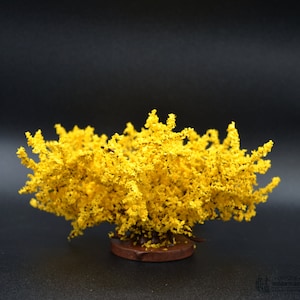 May include: A miniature yellow flowering tree with a brown base. The tree is made of plastic and is perfect for model railroading or other miniature scenes.