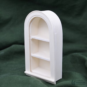 May include: White arched shelf unit with three shelves. The shelf unit is made of a smooth, white material and has a slightly rounded top.