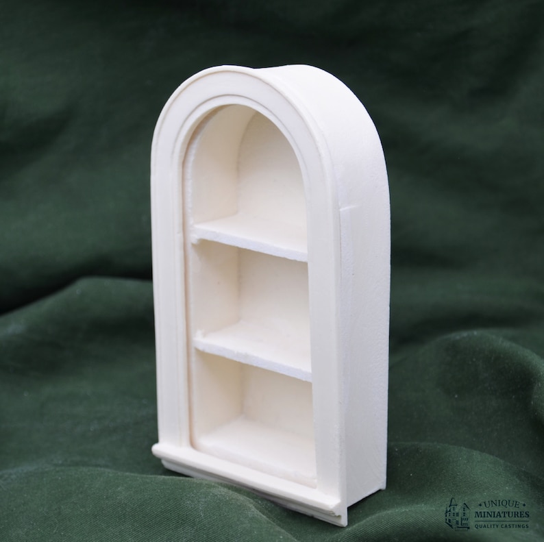 May include: White arched shelf unit with three shelves. The shelf unit is made of a smooth, white material and has a slightly rounded top.