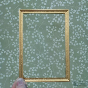 May include: A gold-colored picture frame with a simple, rectangular design. The frame is made of metal and has a smooth, polished finish.