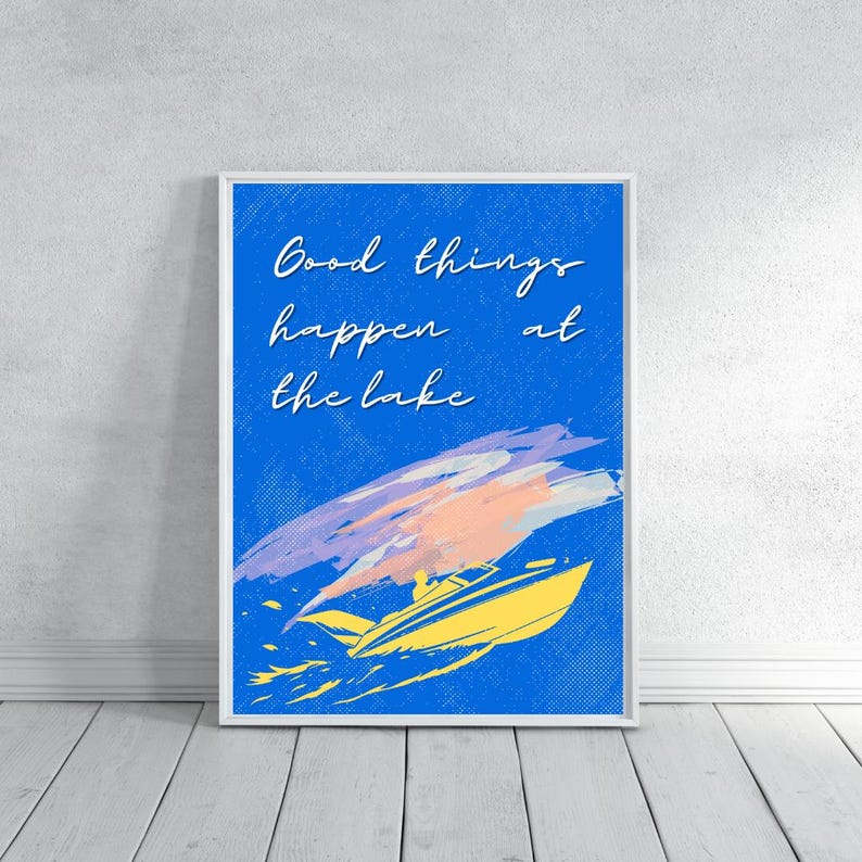 以下が含まれることがあります： 青い背景に「Good things happen at the lake」というテキストが入った額入りのアートプリント。画像には、上にカラフルな筆致のある黄色のスピードボートが描かれています。アートワークは白い壁に表示されています。
