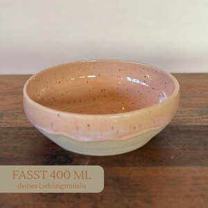 Op de afbeelding: Een keramische kom met een gespikkelde perzik binnenkant en een lichtbeige buitenkant. De kom heeft een inhoud van 400 ml. De tekst op de afbeelding luidt "FASST 400 ML deines Lieblingsm&uuml;slis".