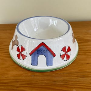 May include: A white ceramic mug with a black handle and the text "But First, Coffee" in a black, bold font. The mug is sitting on a wooden surface. The mug is 4 inches tall.