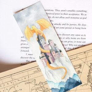 K&ouml;nnte beinhalten: Eine Aquarell-Illustration eines gelben Drachen, der &uuml;ber einem rosa und grauen Schloss fliegt. Der Drache fliegt auf einen blauen und wei&szlig;en Wald zu. Der Text "wh, fusea grow a arrangen forward. I must discover the cu The ques distur" steht auf der linken Seite des Bildes.