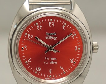 Puede incluir: Reloj de pulsera plateado con esfera roja y correa a juego. La esfera del reloj presenta números arábigos y texto en idioma extranjero. El reloj tiene un diseño clásico y elegante.