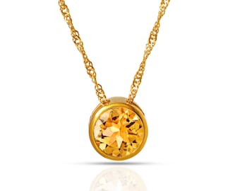 Puede incluir: Un collar de cadena de oro con un colgante redondo que presenta una gran piedra preciosa amarilla transparente.