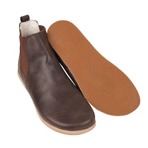 Puede incluir: Botas de tobillo de cuero marrón con suela de goma marrón. Las botas tienen un diseño de fácil calce y una punta ligeramente puntiaguda.