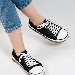 May include: A pair of black canvas low top sneakers with white laces and white rubber soles.