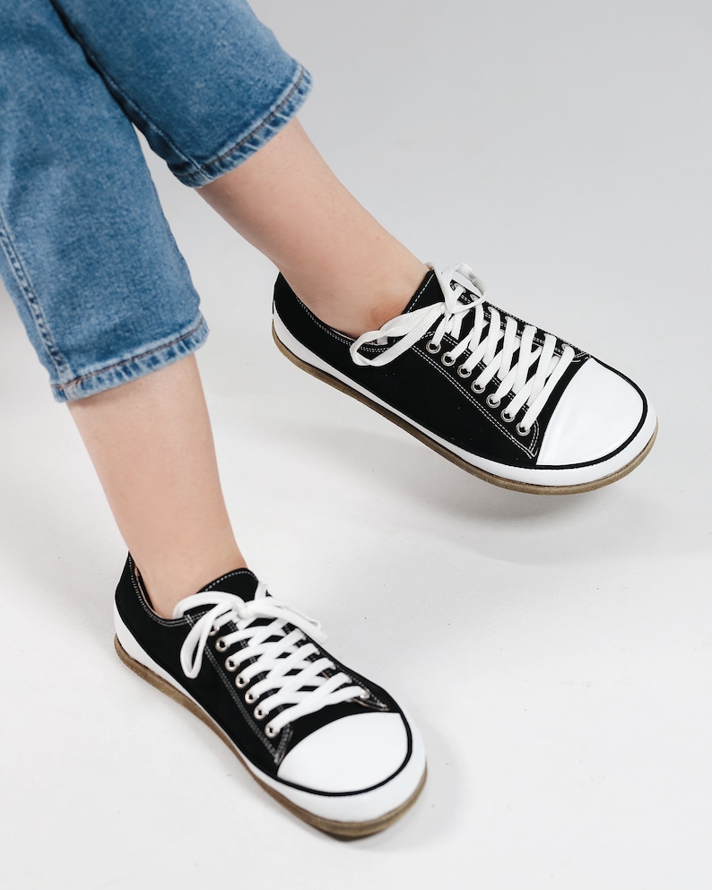 May include: A pair of black canvas low top sneakers with white laces and white rubber soles.