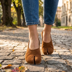 May include: A white ceramic mug with a black handle and the text "But First, Coffee" in a black, handwritten-style font. The mug is on a white surface.