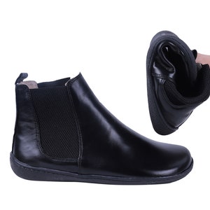 May include: Black leather ankle boots with a pull-on design and a flexible sole.