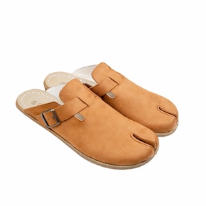 May include: A pair of tan leather clogs with a split toe design. The clogs have a buckle closure and a white interior. The shoes are designed for comfort and style.