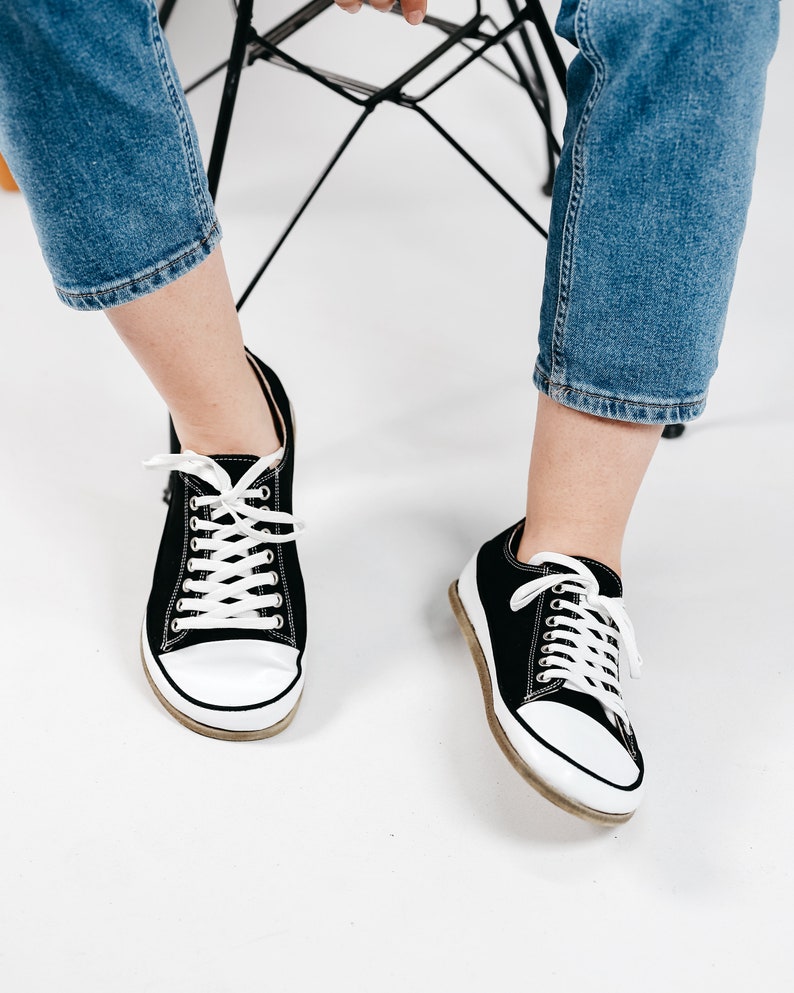 May include: A pair of black canvas low top sneakers with white laces and white soles.
