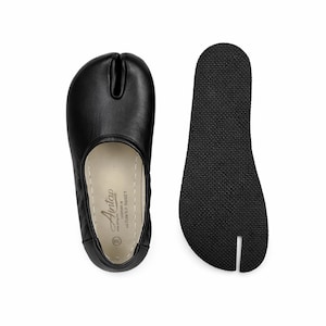 May include: Black leather split-toe shoe with a separate black rubber sole. The shoe has a rounded toe and a split for the big toe. The sole is textured for grip. The shoe is labeled "Antap" and "Made in Gaziantep Turkey".