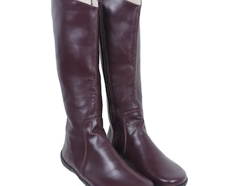 May include: A pair of brown leather knee-high boots with a zipper on the inside of each boot.