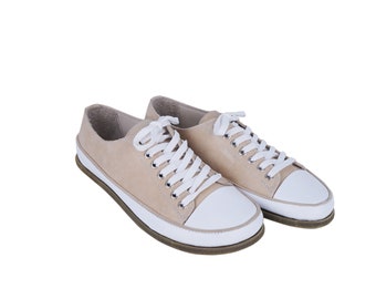 May include: A pair of beige suede low-top sneakers with white laces and white rubber soles.