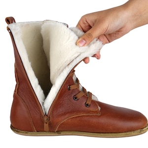 May include: Brown leather boots with a zip and laces. The boots are lined with white faux fur.