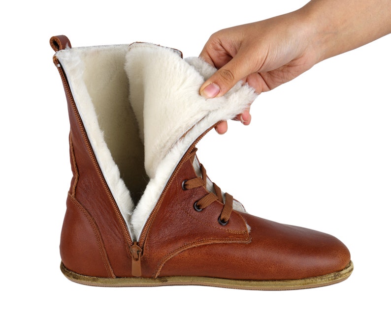 May include: Brown leather boots with a zip and laces. The boots are lined with white faux fur.