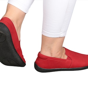 Pode incluir: Sapatos vermelhos de tecido com sola preta. Os sapatos têm um design simples e são feitos de um material macio e confortável.