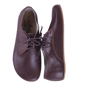 K&ouml;nnte beinhalten: Ein Paar braune Lederschn&uuml;rschuhe mit abgerundeter Spitze. Die Schuhe haben ein schlichtes Design und sind aus hochwertigem Leder gefertigt.