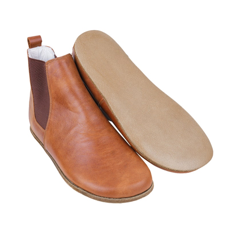 May include: Brown leather ankle boots with a pull-on design and a rubber sole.