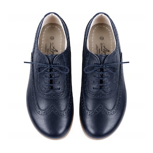Può includere: Un paio di scarpe stringate oxford blu navy scuro con classici dettagli brogue e motivi traforati lungo le cuciture. Le solette interne sono beige chiaro, contrassegnate con la taglia 39 e il marchio AirStep.