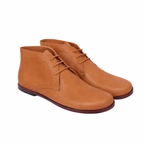 Puede incluir: Un par de botines chukka de cuero color marr&oacute;n claro con cordones a juego. Los botines tienen una puntera redondeada y una suela de perfil bajo. El calzado est&aacute; dise&ntilde;ado para el uso diario y es adecuado para diversas ocasiones.