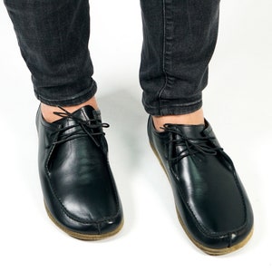 May include: A pair of black leather lace-up shoes with a rounded toe and a brown sole.